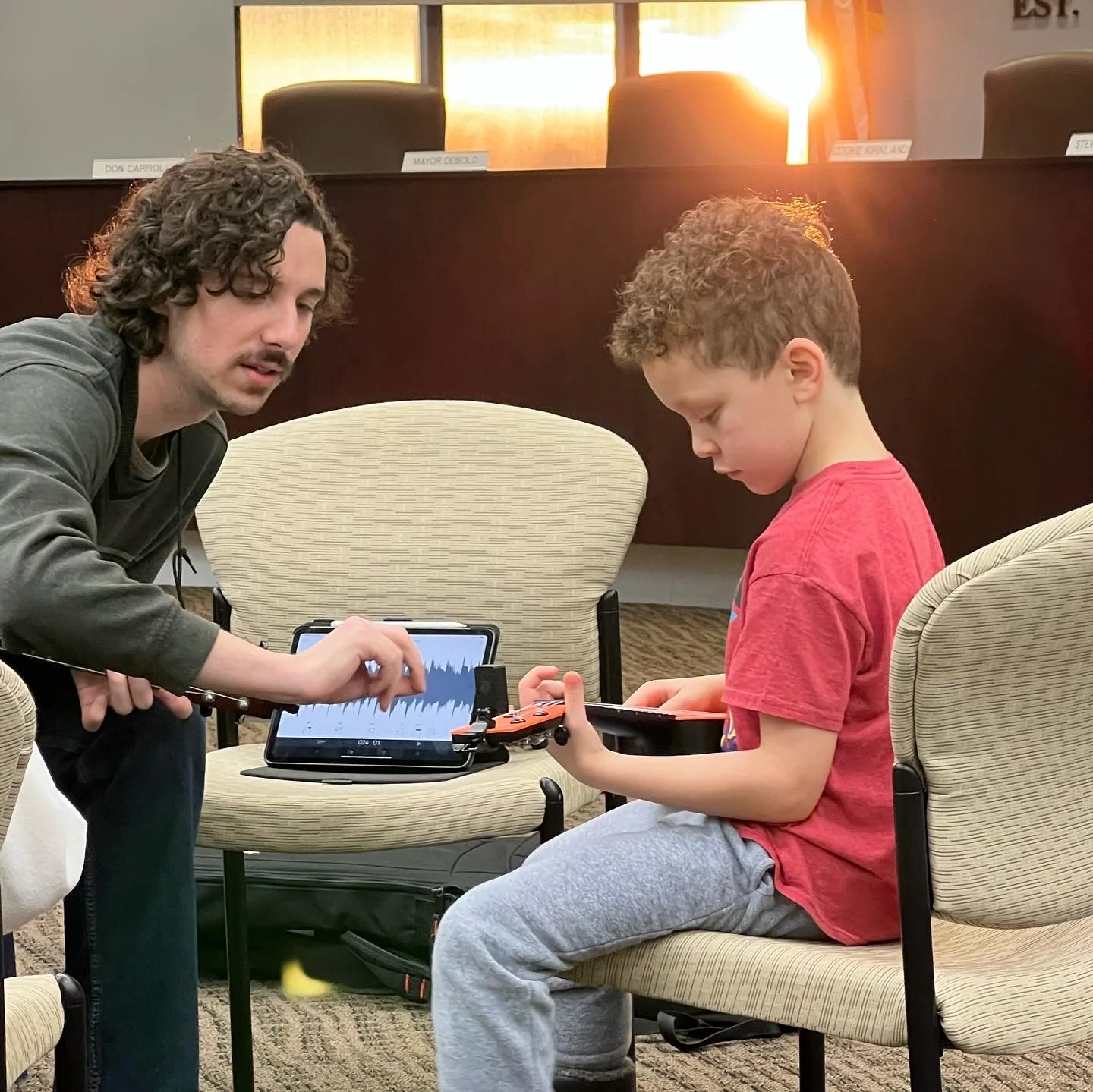 A teacher helping a student understand a musical detail during a ukulele lesson
