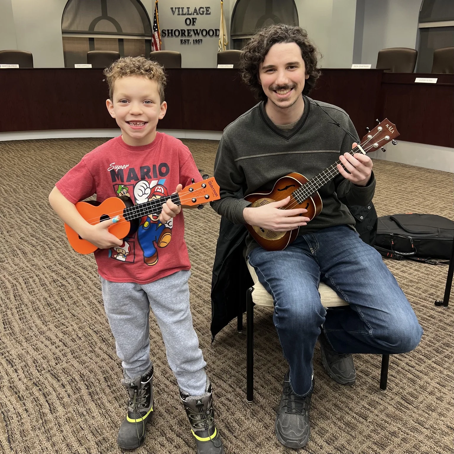 A student and teacher smiling with ukuleles